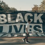 Person walks past Black Lives Matter banner